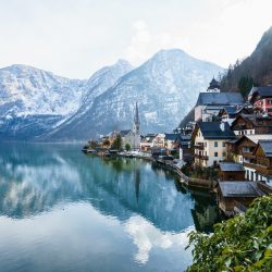 A beautiful shot of a small village surrounded by a lake and snowy hills